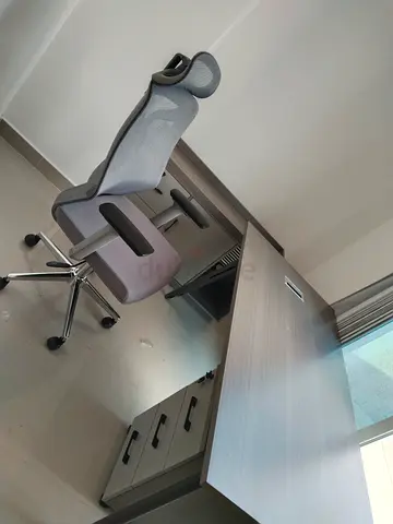 Grey ergonomic office desk with mesh swivel chair and storage drawers