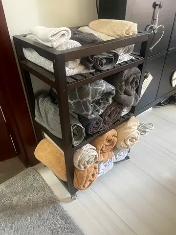 Set of rolled bath towels on wooden storage rack - neutral tones, good condition