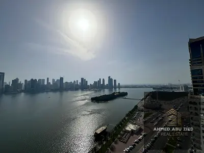 With a direct sea view, the largest two-bedroom apartment with a living room is available for annual rent in Sharjah, featuring a large modern kitchen