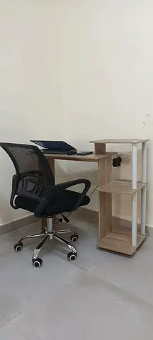 Compact wooden study desk with a regular office chair and shelving unit