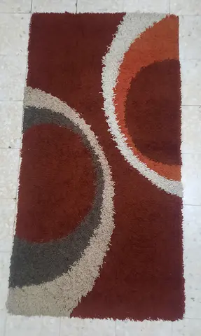 Used shaggy rectangular area rug with circular modern pattern - rust/brown