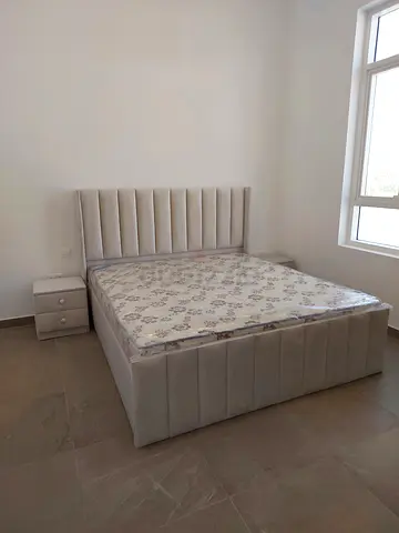 Light grey upholstered queen bed with mattress and bedside drawer