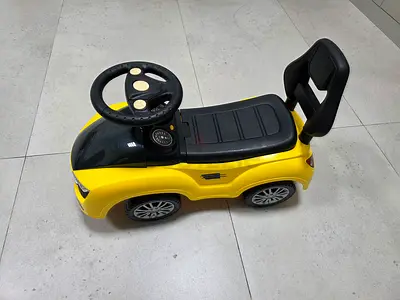 Yellow ride-on toy car with steering wheel and backrest — good condition