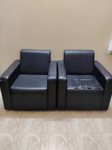 Pair of black faux leather armchairs — used, one with seat tear