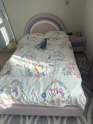 Single kids bed with pastel rainbow headboard and floral bedding