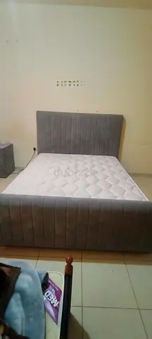 Grey upholstered double bed with mattress