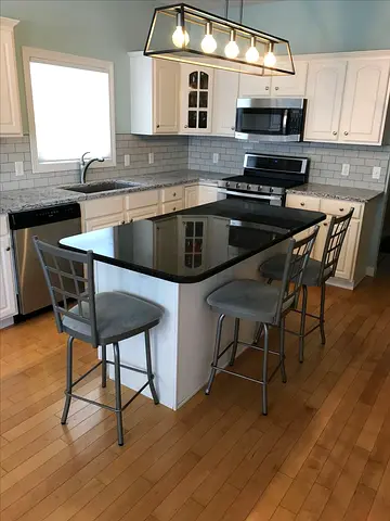 Kitchen island with 3 metal bar stools and granite top