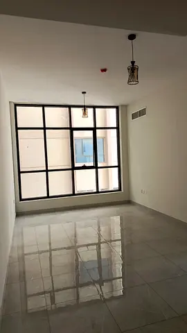 For rent in Muwaileh – brand new 2BR + hall, 3 baths, semi-closed kitchen, free parking & gym, maintenance included, prime location opposite park.