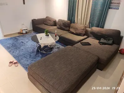 Large L-shaped brown fabric sectional sofa in good condition with center table.