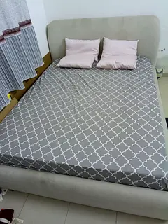 Light grey upholstered queen size bed with cushioned headboard with mattress