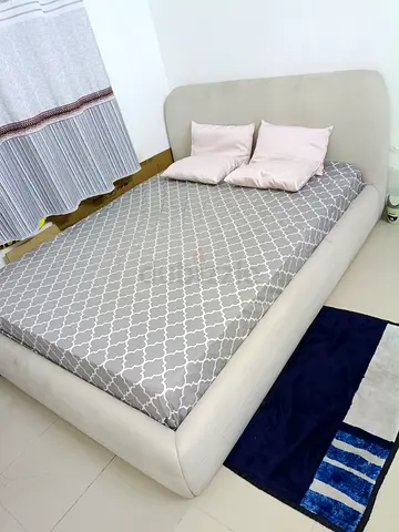 Light grey upholstered queen size bed with mattress