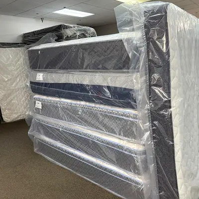 Brand new stacked mattresses — various sizes, still shrink-wrapped