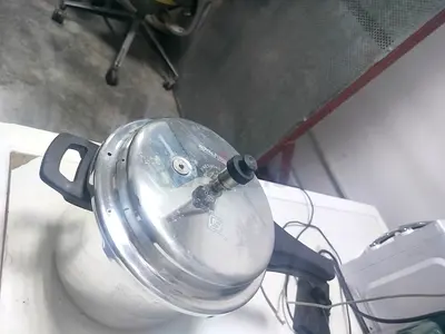 Used stainless steel pressure cooker with lid and handles