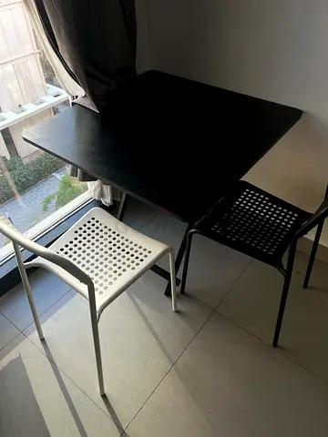 Simple black dining table with two modern perforated chairs
