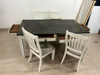 An antique white dining table with a dark wood top and rustic design.