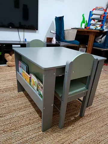 Kids table and two chairs set with built-in book storage on both sides of the table