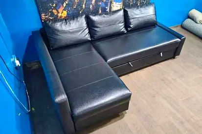 Black L-shaped leather sofa with storage, good condition