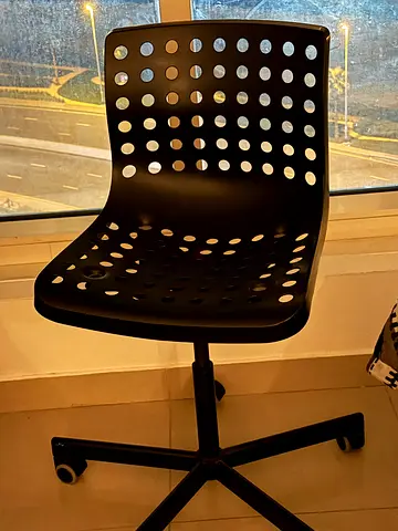 Black swivel office chair with perforated plastic back and seat