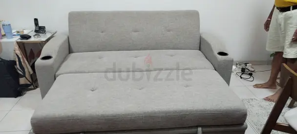 Grey fabric sofa bed with armrest cup holders - good condition