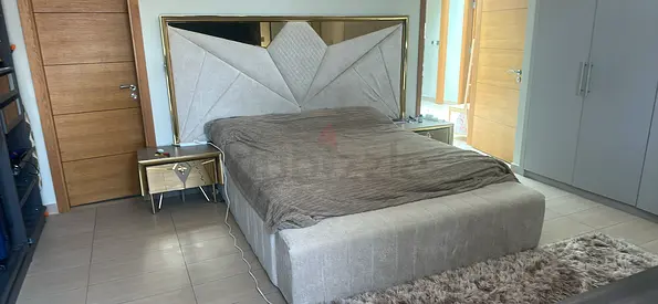 King-size upholstered bed with mirrored headboard and bedside tables