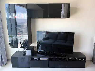 Modern glossy black TV console with wall-mounted cabinet