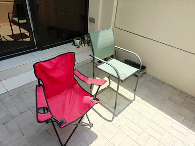 Two outdoor chairs — folding camping chair and metal patio chair