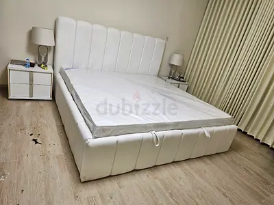 White upholstered double bed with mattress and headboard