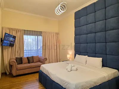 King bed with tall upholstered headboard and matching base with 2 side tables and lamps