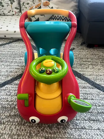 Red and green toddler ride-on walker with steering wheel and music