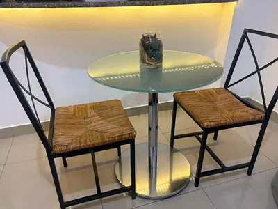 Small round glass bistro table with two woven-seat chairs