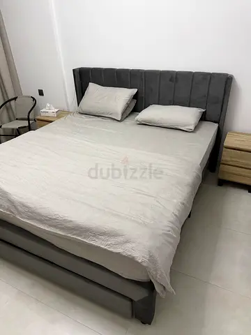 Grey upholstered king bed frame with headboard and storage base.