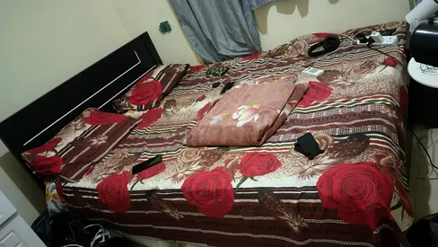 Queen-size bed frame with mattress and floral bedding (used)