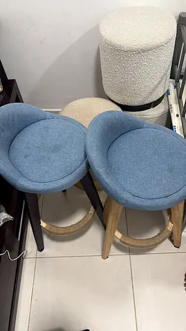 3 beige ottomans with soft textured fabric and gold base. Plus 2 modern blue bar stools with cushion