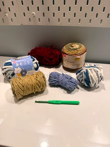 Bundle of assorted yarn skeins with crochet hook - good condition