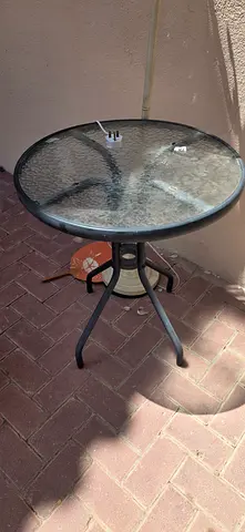 Small round outdoor glass-top bistro table with metal base