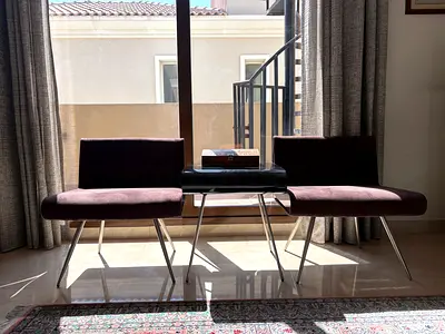 Pair of modern armless accent chairs with metal legs and side table