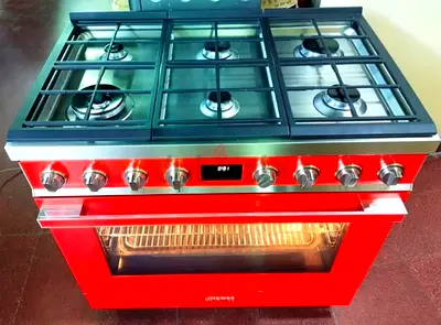 Smeg Portofino freestanding range cooker in red, featuring 6 gas burners