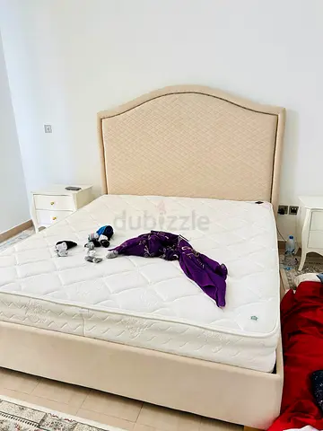 Beige upholstered king bed frame with mattress