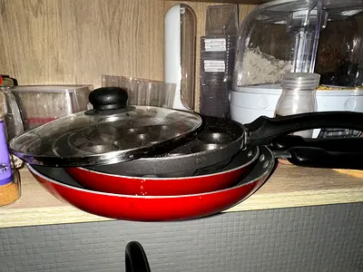 Set of three non-stick frying pans with glass lid and other utensils