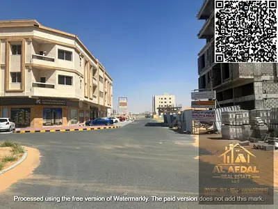 Residential/commercial land for sale on a corner lot with two street frontages in Ajman, Al Alia Global area. Ownership is available to all nationalit