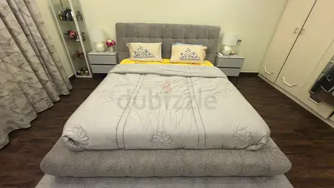 Light grey upholstered king bed with padded headboard (brand new), with side tables, dressing table
