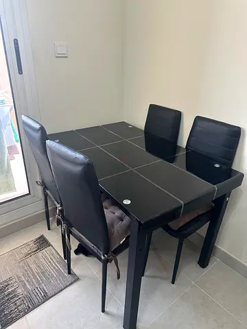 Black glass-top dining table with 4 faux leather chairs - good condition