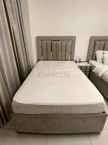 Grey upholstered bed frame with headboard and mattress