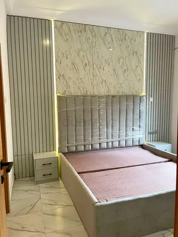 Upholstered double bed with built-in headboard panels and bedside drawers