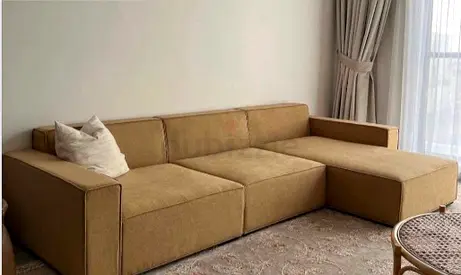 A modern sectional sofa L shaped brown gold colour
