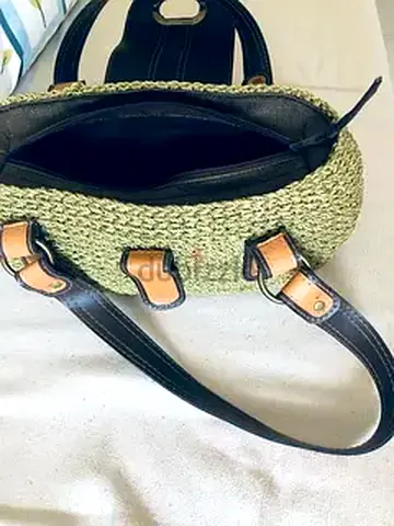 Woven straw tote bag with black leather handles