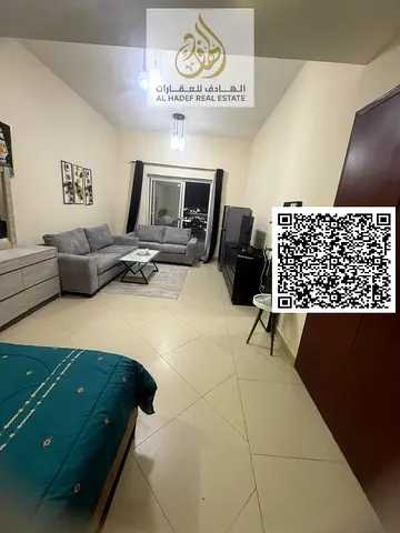 Furnished studio apartment in Al Nuaimiya 1, Al Shurooq Towers. Features a semi-separate kitchen and balcony, high-end furnishings, and a spacious lay