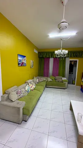 Large L-shaped green fabric sofa in good condition