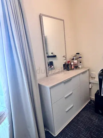 Light grey dresser with mirror and three drawers with one side closet