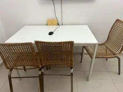 Simple white study table with two woven rattan chairs